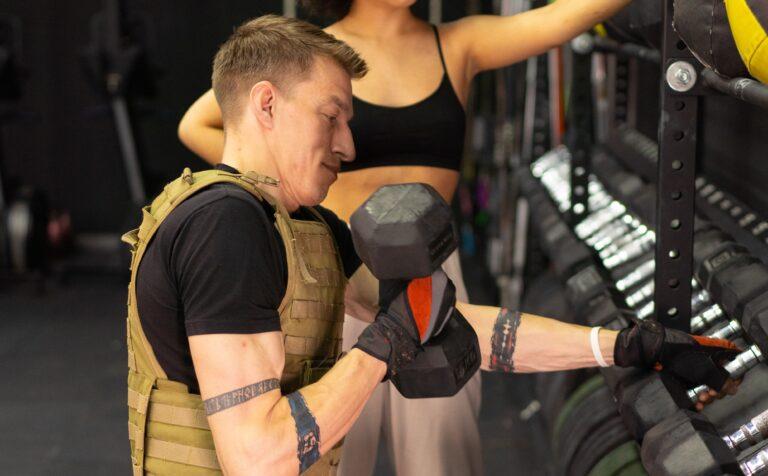Side View of a Man in a Weighted Vest Holding a Dumbbell
